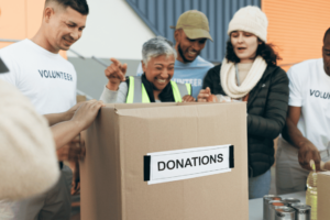 A group of people putting food into a box. Nonprofit organizations and the Community Development Financial Institution (CDFIs) play a crucial role in fostering community development and addressing social and economic challenges
