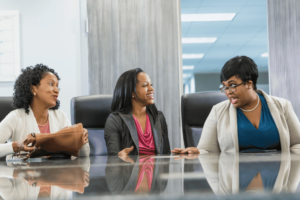 A group of women sitting at a table. Minority-owned businesses are enterprises that are owned and operated by individuals from ethnic or racial minority groups. 